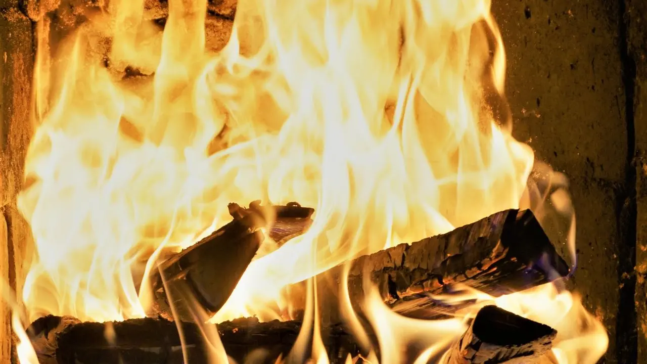 Wood burning in a soot-blackened fireplace firebox — creosote left behind is the usual source of fireplace smell