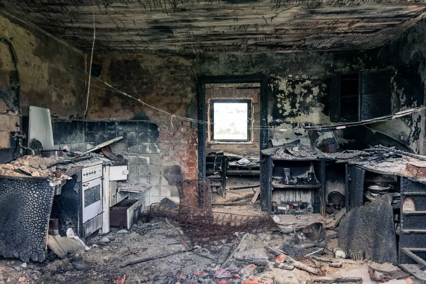 Fire-damaged kitchen interior with charred walls, blackened cabinets, and heavy soot residue — illustrative of the cleanup we handle for Boca Raton homeowners after a kitchen fire.