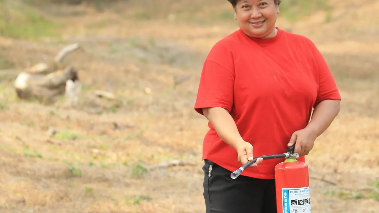 A person holding a red fire extinguisher — choosing the right class is critical for kitchen grease fires