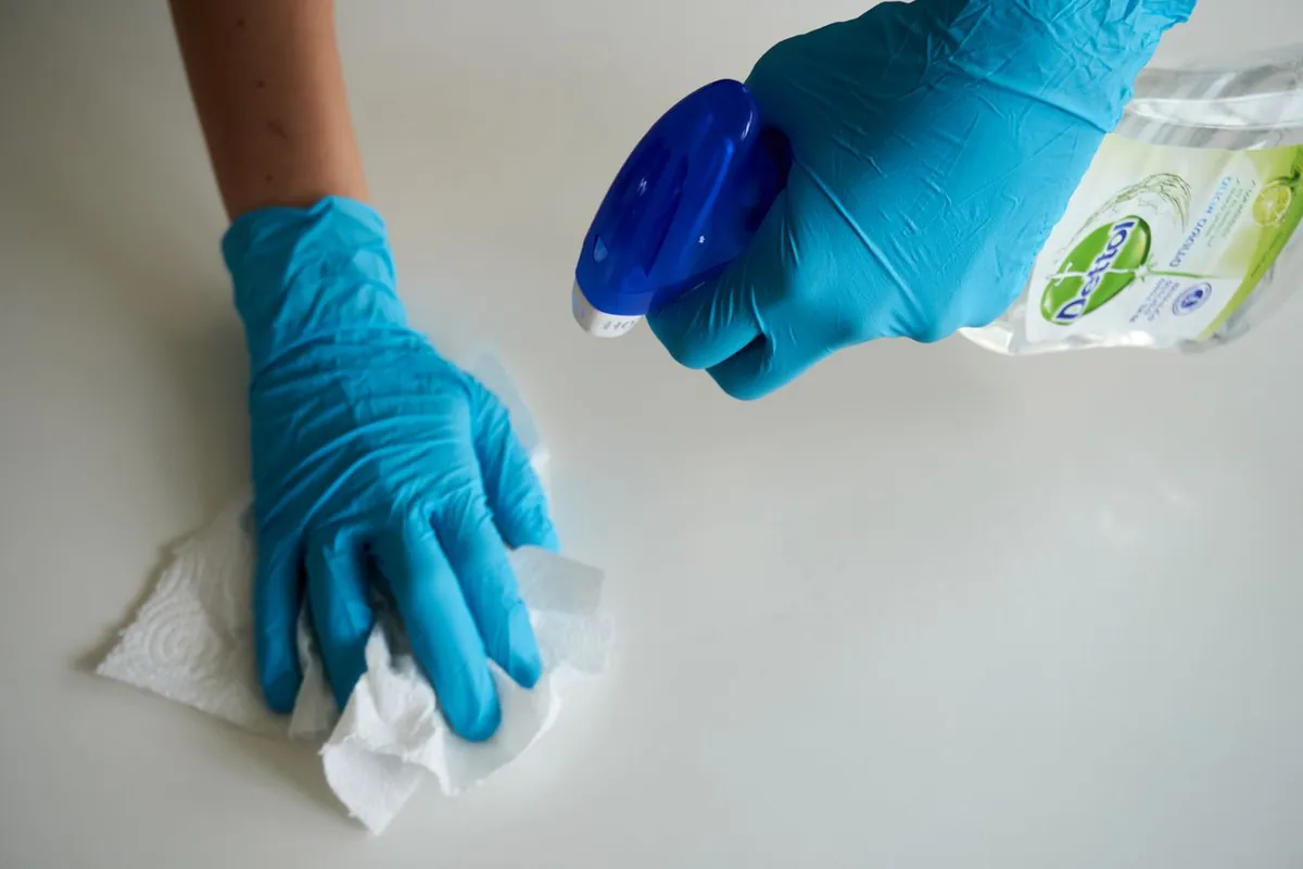 Gloved technician wiping greasy soot residue from a surface