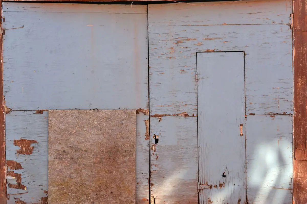 Boarded-up window opening on a damaged building — securing the structure against weather and entry after a fire