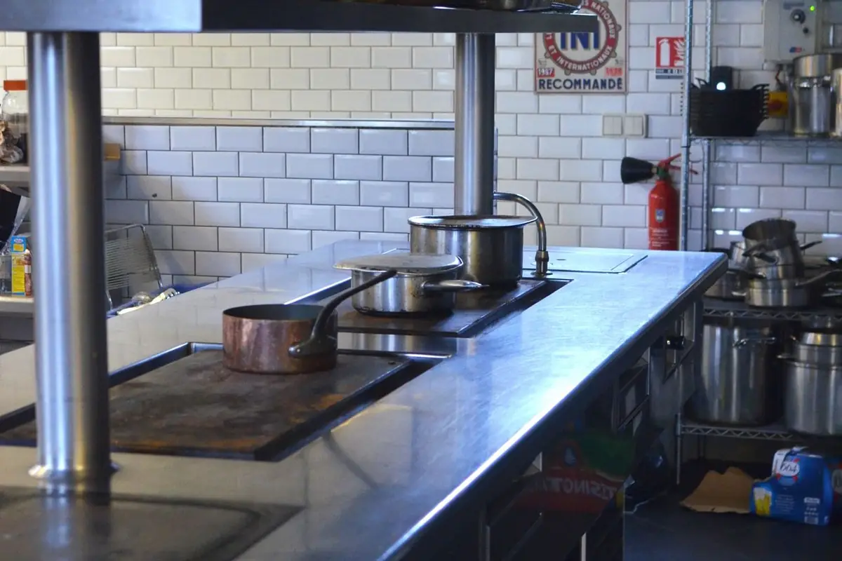 Commercial kitchen line with extraction hood — after a suppression discharge the system must be recharged and certified before reopening