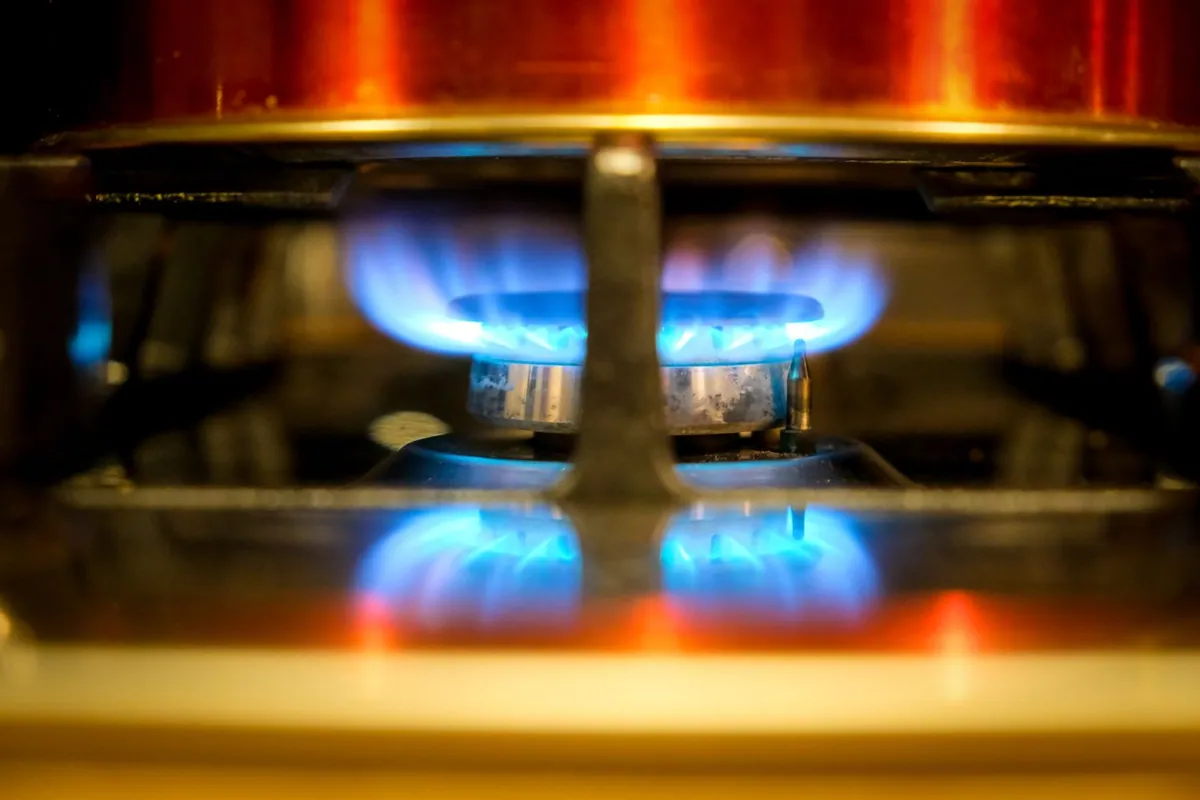 Gas stove burner flame under a pan — a yellow flame deposits black soot on cookware and signals incomplete combustion